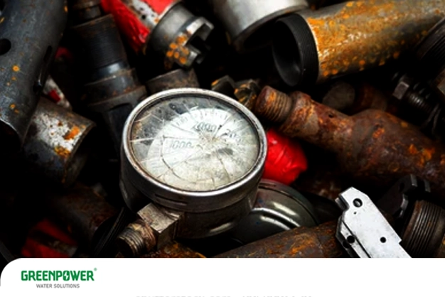 تصویر یک گیج فشار به‌شدت زنگ‌زده و کدر که در میان قطعات فلزی فرسوده قرار دارد و نشان‌دهنده خرابی گیج تصفیه آب بر اثر خوردگی شدید و عدم نگهداری صحیح است.