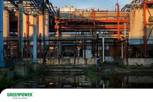 نمایی از یک واحد صنعتی فرسوده با مخازن و لوله‌های زنگ‌زده و تجمع آب آلوده در کف محوطه؛ تصویری که بیانگر نقش صنایع در ایجاد عوامل آلوده‌کننده آب و تهدید منابع آبی است.